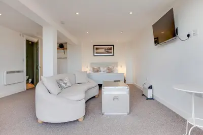 a living room with a white couch and a tv at Studio Lodge with parking - Stansted airport in Hatfield Broad Oak