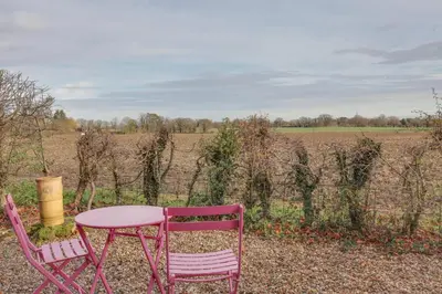 a pink table and two chairs sitting next to a field at Studio Lodge with parking - Stansted airport in Hatfield Broad Oak