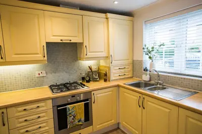 a kitchen with yellow cabinets and a sink and a stove at Your home away from home in Bury Saint Edmunds