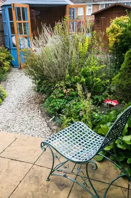a bench sitting on a sidewalk in a garden at Your home away from home in Bury Saint Edmunds