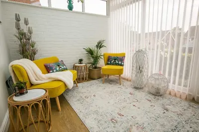 a living room with two yellow chairs and a rug at Your home away from home in Bury Saint Edmunds
