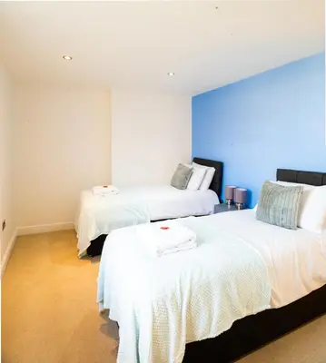 two beds in a room with a blue wall at Cozy 2BR 2BATH Apt in Central Ipswich - Sleeps 6 & Prime Location in Ipswich