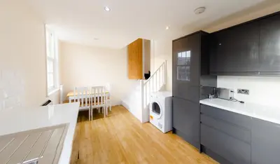 a kitchen with black cabinets and a washer and dryer at Cozy 2BR 2BATH Apt in Central Ipswich - Sleeps 6 & Prime Location in Ipswich