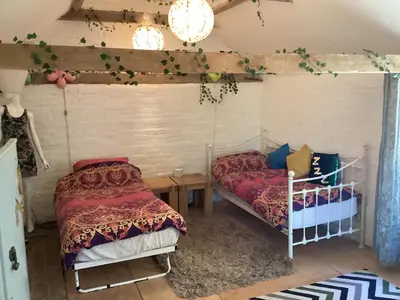 a bedroom with two beds and a table at The Eclectic Coach House in Roydon