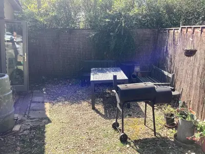 a barbecue grill in a backyard with a fence at The Eclectic Coach House in Roydon