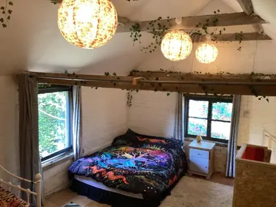 a bedroom with a bed and two chandeliers at The Eclectic Coach House in Roydon