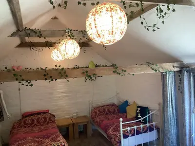 a room with two beds and two chandeliers at The Eclectic Coach House in Roydon