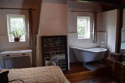 a bathroom with a tub and a bed and windows at Countryside Tiny House in Roydon