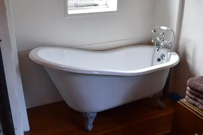 a white bath tub in a bathroom with a window at Countryside Tiny House in Roydon