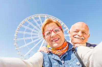 an older couple standing in front of a ferris wheel at Cosy Caravan With Decking At Oaklands Holiday Park In Essex Ref 39042Cf in Clacton-on-Sea