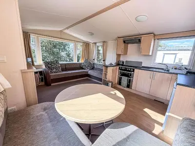 a kitchen and living room with a table in a caravan at Cosy Caravan With Decking At Oaklands Holiday Park In Essex Ref 39042Cf in Clacton-on-Sea