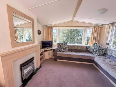 a living room with a couch and a fireplace at Cosy Caravan With Decking At Oaklands Holiday Park In Essex Ref 39042Cf in Clacton-on-Sea