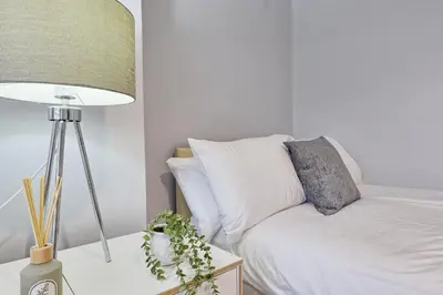 a bedroom with a bed and a table with a lamp at 5 Bedroom Apartment - Weekly Deal - By Homestyles Hosts Short Lets and Serviced Accommodation Widford - Free Parking in Writtle