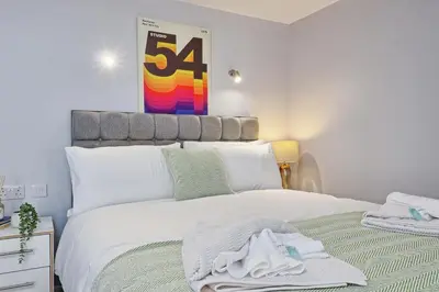 a bedroom with a large white bed with towels on it at Studio By Homestyles Hosts Short Lets & Serviced Accommodation Widford - Free WiFi in Writtle