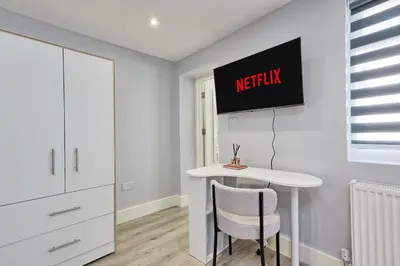 a kitchen with a white table and a tv on the wall at Studio By Homestyles Hosts Short Lets & Serviced Accommodation Widford - Free WiFi in Writtle