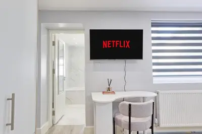 a bathroom with a white table and a tv on the wall at Studio By Homestyles Hosts Short Lets & Serviced Accommodation Widford - Free WiFi in Writtle