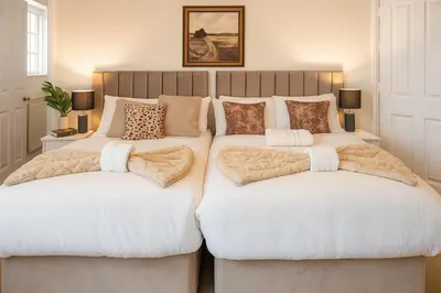 a bedroom with two beds with white sheets at Relaxing Coastal Getaway Perfect for Families in Canvey Island