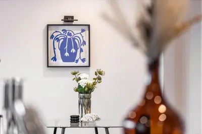a vase with flowers on a table with a picture at Relaxing Coastal Getaway Perfect for Families in Canvey Island
