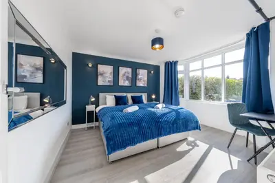 a bedroom with blue walls and a bed and a sink at Free parking - 6 Bedroom Home in Colchester