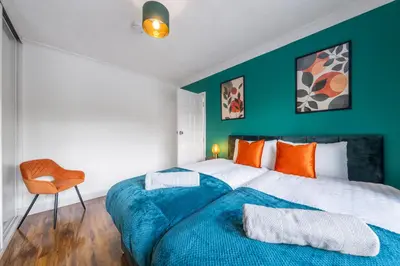 a bedroom with a blue and white bed and a chair at Free parking - 6 Bedroom Home in Colchester