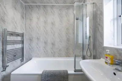 a bathroom with a bath tub and a sink at Free parking - 6 Bedroom Home in Colchester