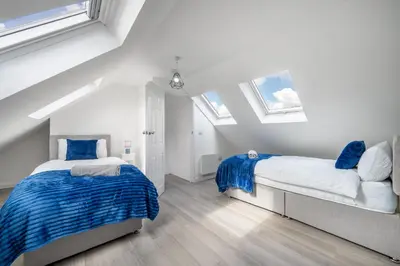 two beds in a white room with skylights at Free parking - 6 Bedroom Home in Colchester