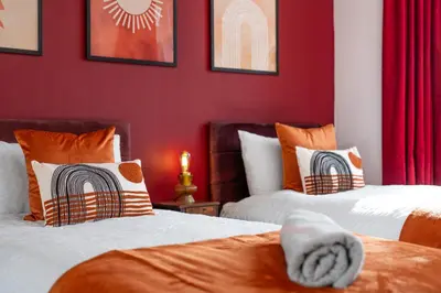 two beds in a room with red walls at Free parking - 6 Bedroom Home in Colchester