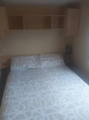 a bedroom with a bed with a white comforter at Seaside caravan in Clacton-on-Sea
