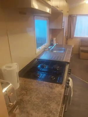 a kitchen with a stove and a sink with a window at Seaside caravan in Clacton-on-Sea