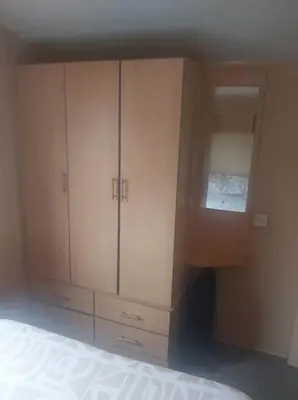 a bedroom with a bed and a large wooden cabinet at Seaside caravan in Clacton-on-Sea