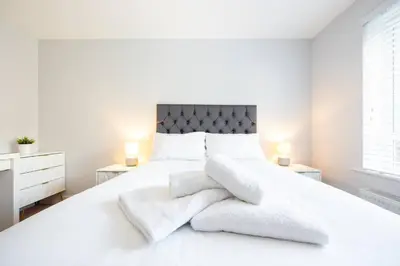 a white bedroom with a large white bed with towels on it at 3bed town house- Superking Beds-fast WI-FI-Parking in Colchester