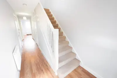 a staircase in a home with white walls and wooden floors at 3bed town house- Superking Beds-fast WI-FI-Parking in Colchester