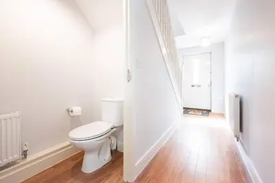 a white bathroom with a toilet and a hallway at 3bed town house- Superking Beds-fast WI-FI-Parking in Colchester