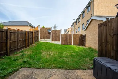 a yard with a wooden fence and a building at 3bed town house- Superking Beds-fast WI-FI-Parking in Colchester
