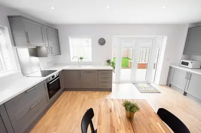 a kitchen with gray cabinets and a wooden table at 3 Bed 2.5 Bath Detached House,Parking,Pet Friendly in Parkeston