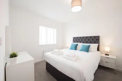 a white bedroom with a large bed with blue pillows at House -Superking Beds-Garden-FastWifi-Pet Friendly in Broomfield