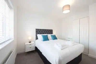 a white bedroom with a large bed with blue pillows at House -Superking Beds-Garden-FastWifi-Pet Friendly in Broomfield