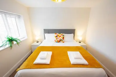 a bedroom with a large bed with two towels on it at 6 The Royal Serviced Apartments, Harwich - Fast WiFi, Private Parking in Parkeston