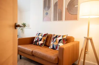a brown couch in a living room with a lamp at 6 The Royal Serviced Apartments, Harwich - Fast WiFi, Private Parking in Parkeston