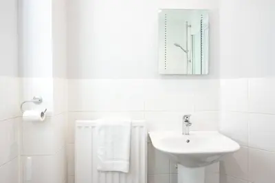 a white bathroom with a sink and a mirror at Two Double Bed Coach House with Parking Fast WiFi in Colchester