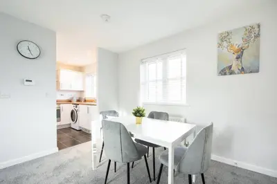 a white dining room with a white table and chairs at Two Double Bed Coach House with Parking Fast WiFi in Colchester