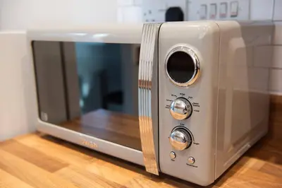 a microwave oven sitting on top of a wooden floor at Two Double Bed Coach House with Parking Fast WiFi in Colchester