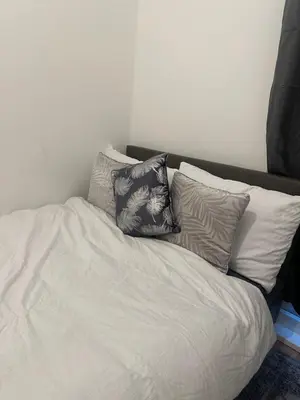 a white bed with three pillows on top of it at The Retreat On Retreat Road in Southend-on-Sea
