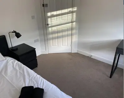 a bedroom with a bed and a door with a lamp at 4 Bedroom House Colchester in Colchester