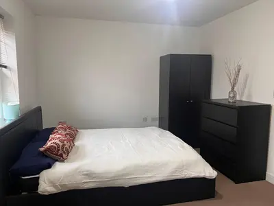a bedroom with a bed and a black dresser at 4 Bedroom House Colchester in Colchester