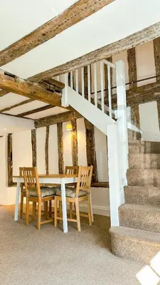 a dining room with a table and chairs and stairs at One Threadneedle Street, Dedham in Dedham
