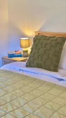 a bed with a pillow and a table with a lamp at One Threadneedle Street, Dedham in Dedham
