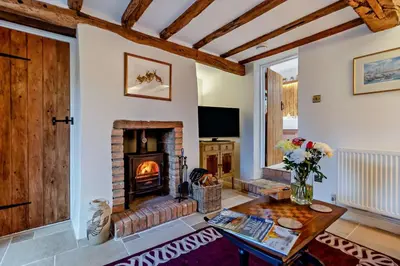 a living room with a fireplace and a table at 1 Bed in Snape oc-a30669 in Snape