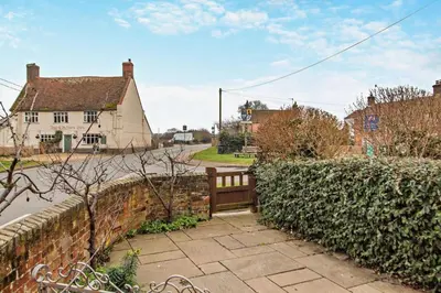 a wooden bench sitting on a sidewalk next to a wall at 1 Bed in Snape oc-a30669 in Snape