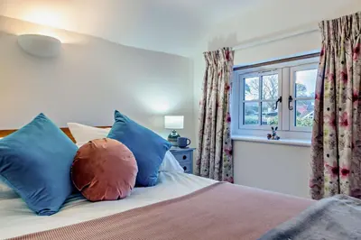 a bedroom with a bed with colorful pillows and a window at 1 Bed in Snape oc-a30669 in Snape